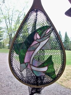 a stained glass window hanging from the side of a building with a fish on it