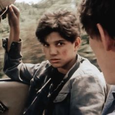 a young boy sitting in the back seat of a car looking at another man's face