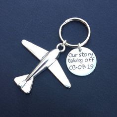 a silver keychain with an airplane on it that says our story is taking off