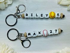 two keychains with baseballs and numbers on them sitting next to each other