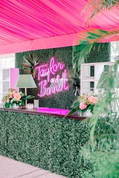 a pink neon sign on the side of a green wall next to a lamp and potted plant