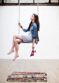 a woman is sitting on a swing with her feet in the air and looking up