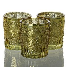 Richland Mercury Votive Holders Primrose Metallic Gold Set of 12. The most lovely combination of mercury style, textured glass, and intricate design make our Primrose Mercury Votive Holder a must-have! This light gold glass holder has a thick sham and raised textured body with four design-filled circles - this adds to the intrigue of the design and catches the glimmer of candlelight. Fill with our Richland Votive or Tealight candles; and the effect of glowing light is stunning through the speckled silver interior. Mercury Candle Holders, Gold Votives, Bouquet Succulent, Glass Cup Set, Tealight Candles, Candle Glow, Votive Holder, Glass Holder, Vintage Candle Holders