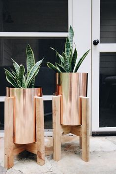 two wooden planters sitting next to each other on top of a stone floor in front of a door