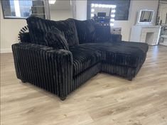 a large black couch sitting on top of a hard wood floor next to a mirror