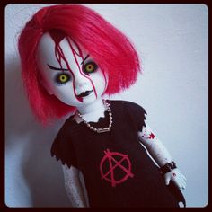 a creepy doll with red hair and green eyes wearing a t - shirt that says anarchy