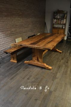 a wooden table sitting on top of a hard wood floor next to a brick wall