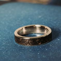 a close up of a wedding ring on a blue surface with small speckles