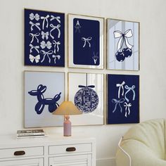 four blue and white art pieces hang on the wall above a dresser in a living room