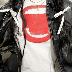 a woman with long hair wearing a white shirt and black leather jacket, has her mouth painted red