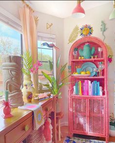 a pink book shelf in the corner of a room filled with books and other items