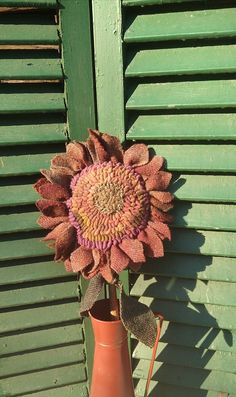 a vase with a knitted sunflower in it sitting next to a green wall