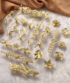 a collection of gold brooches and pins on a white surface with a brown cloth