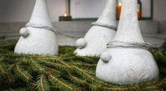 three white statues sitting on top of a pile of pine needles