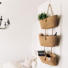 three baskets are hanging on the wall in front of a bed and chandelier