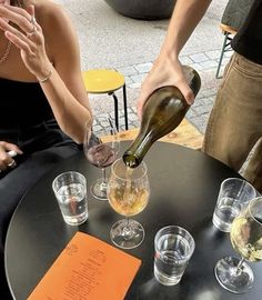 a woman pours wine from a bottle into glasses