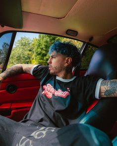 a man with blue hair sitting in the back seat of a car