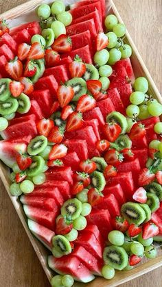 watermelon, kiwi and grapes arranged on a platter for a party