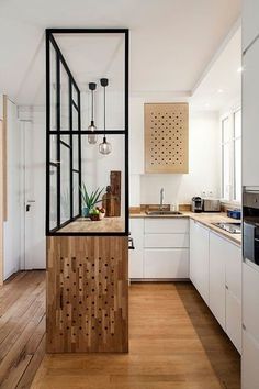 a kitchen with white cabinets and wood floors, along with an island in the middle