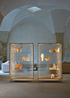 two glass cases with vases on them in a room filled with stone walls and arches