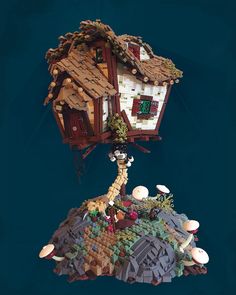 a house made out of legos on top of a hill with trees and mushrooms