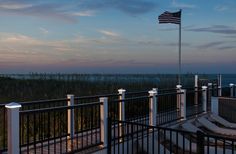 an american flag is flying on the top of a balcony overlooking the ocean at dusk