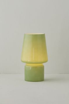 a yellow and green lamp sitting on top of a white table next to a wall