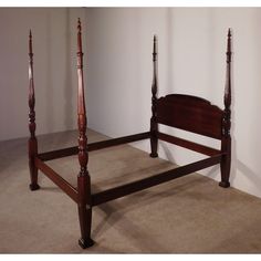 a wooden bed frame sitting on top of a carpeted floor next to a white wall