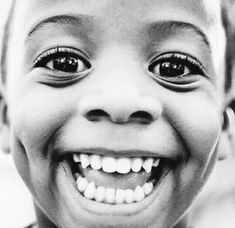 a black and white photo of a young boy with big eyes smiling at the camera