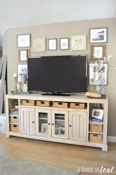 a flat screen tv sitting on top of a white entertainment center with baskets underneath it