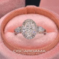 an oval shaped diamond ring with three smaller diamonds on it's band in a pink velvet box