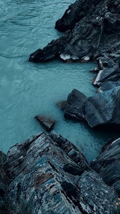 the water is very blue and there are rocks on the shore next to it that look like they're floating in the ocean