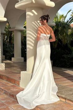 a woman in a white wedding dress standing on some steps with her back to the camera