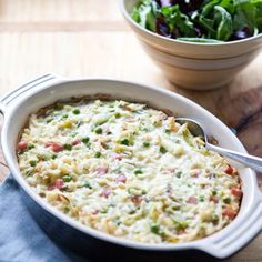 a white casserole dish filled with pasta and veggies next to a salad