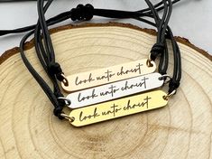 three necklaces with words on them sitting on a piece of wood