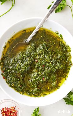 a white bowl filled with pesto sauce and garnished with chopped parsley