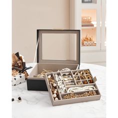 an open jewelry box sitting on top of a white table next to other boxes filled with beads