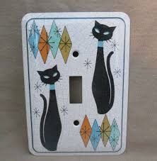 a light switch cover with black cats on it's side and colorful diamonds in the background