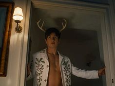 a shirtless man with antlers on his head standing in front of a door