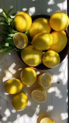 a bowl full of lemons sitting on top of a table next to sliced lemons