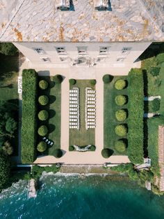 an aerial view of the pool and lawns in front of a large white building