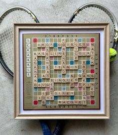 a framed scrabble puzzle with tennis racquets on the ground next to it