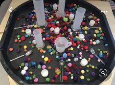 the tray is filled with different colored beads and plastic cups, spoons and forks