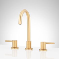 two gold faucets on a white surface