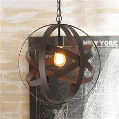 a light fixture hanging from the side of a brick wall with a new york sign in the background