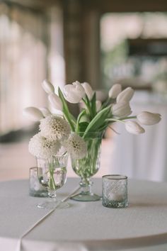 two vases filled with white flowers on top of a table