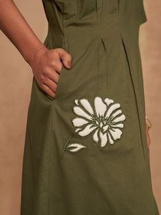 a woman's green dress with white flower embroidered on the front and back side