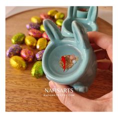 a hand holding a blue bunny bowl with chocolate eggs in it and candy candies on the side