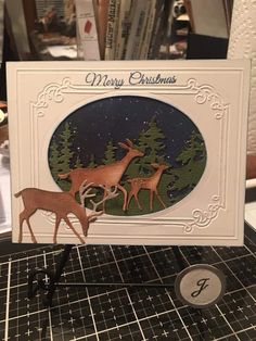 a christmas card with three deers in the woods on it, surrounded by books