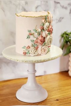 there is a white cake with flowers on the top and gold trim around the edges